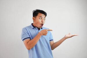 shocked asian man with an open hand with fingers pointing to the side wearing blue t shirt isolated on white background photo