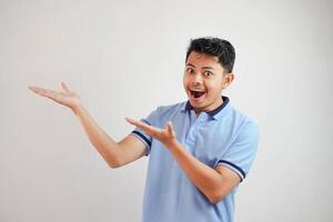 shocked asian man with an open hand with fingers pointing to the side wearing blue t shirt isolated on white background photo