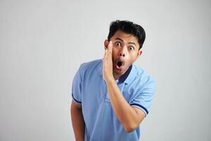 retrato de un joven asiático hombre gritando fuera ruidoso con mano a su boca vistiendo azul t camisa aislado terminado blanco antecedentes foto