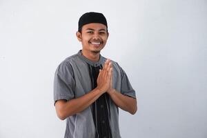 young Asian Muslim man wearing koko clothes smiling to give greeting during Ramadan and Eid Al Fitr celebration isolated on white background photo