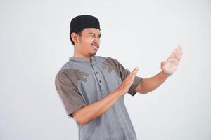 Serious young Asian Muslim man hands makes stop gesture and demonstrates rejection wearing kurta clothes isolated on white background photo
