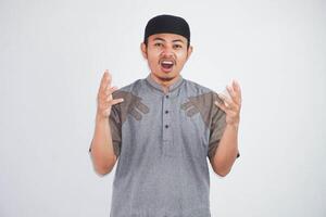 Annoyed Asian Muslim man shouts loudly expresses rage wearing muslim clothes isolated on white background photo