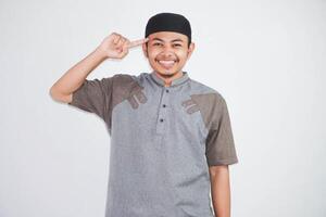 happy asian muslim man pointing head wearing grey muslim clothes isolated on white background photo