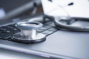 grey Stethoscope on laptop or on the keyboard of pc, close-up. macro view of a grey stethoscope on a business office laptop keyboard with selective focusing effect photo