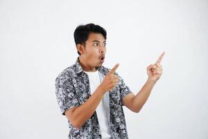 shocked asian man with fingers pointing to the side wearing black shirt isolated on white background photo