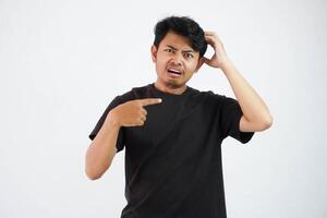 shocked asian man with fingers pointing to the side wearing black t shirt isolated on white background photo