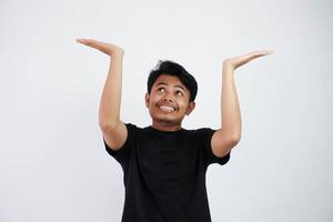 Young Asian man in black casual clothes attempt to hold something heavy from above. isolated on white background photo
