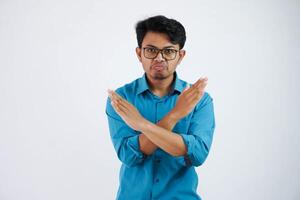 young Asian businessman wearing blue shirt with glasses show cross arms for disagree say no isolated on white background photo