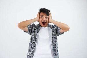 shouted or shocked young asian man holding head with mouth open wearing white t shirt isolated photo