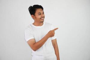 sonriente asiático hombre con dedos señalando a el lado vistiendo blanco t camisa aislado en blanco antecedentes foto