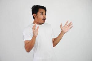 shock asian man with open hands and mouth wearing white t shirt isolated on white background photo