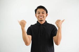 smiling asian man thumb pointing ti the right and left side, confused to choose something wearing black polo t shirt isolated on white background photo