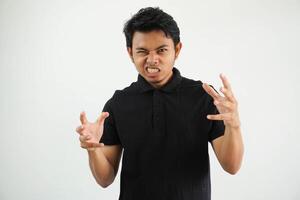 Portrait of angry pensive crazy Asian young man screaming wearing black polo t shirt isolated on white background photo