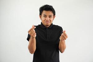 smiling or happy asian man showing gesture heart shape hands or crossing his index finger and thumb the symbol saranghae, sarangheo, saranghaeo wearing black polo t shirt isolated photo