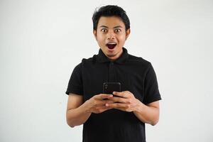 surprised or shocked young asian man isolated on white background holding phone looking camera and sending a message photo