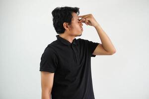 Casual young asian man against a vibrant white studio background, having a head ache, touching front of the face, wearing black polo t shirt photo
