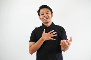 joven asiático hombre sonriente simpático y haciendo acogedor actitud con manos presionado a el cofre y abierto brazos vistiendo negro polo t camisa aislado en blanco antecedentes foto