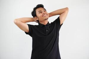 young asian man posing on a white backdrop stretching arms, relaxed position. wearing black polo t shirt. photo