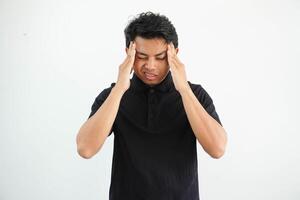 Portrait of young asian man isolated on white background suffering from severe headache, pressing fingers to temples, closing eyes to relieve pain with helpless face expression photo