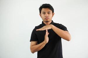 joven asiático hombre en negro polo t camisa, estudio Disparo en blanco fondo demostración un se acabó el tiempo gesto. foto