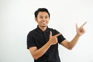 young asian man smiling confident with both hand pointing to the left side wearing black polo t shirt isolated white background photo