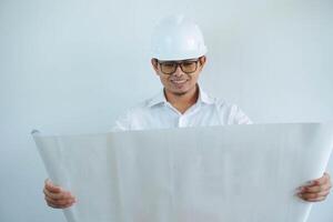 young asian male architect engineer smiling and Holding engineering blueprints isolated on white background. photo