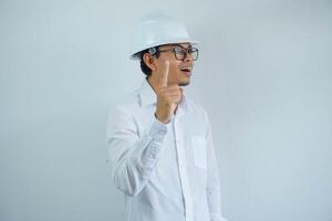 joven asiático arquitecto hombre vistiendo constructor la seguridad casco terminado aislado antecedentes señalando dedo arriba con exitoso idea. salido y contento. número uno. foto