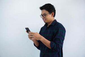 sonriente o contento cara joven asiático hombre mientras utilizando móvil teléfono aislado blanco antecedentes foto