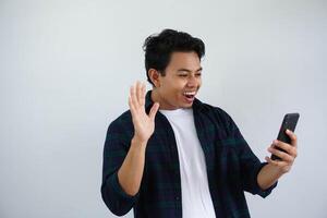 young asian man looking to his mobile phone with wow expression isolated on white background. photo