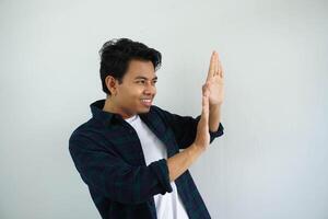 young asian man showing expression of holding something from the side that was extremely heavy, copy space isolated on white background. photo