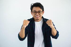 young asian man glasses looking camera with both hands clenched showing excitement isolated on white background. photo