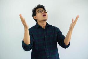 young Asian man looks up showing a regretful expression with his arms open isolated on white background photo