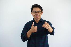 smiling young asian man pointing forward while giving thumb up isolated on white background. photo