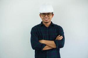 young asian man is engineer wearing helmet standing with crossed arms and smiling with confident, architect or contractor, worker or labor, industrial concept. photo