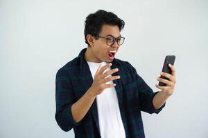 young asian man showing rage expression when looking to his cellular phone isolated on white background. photo