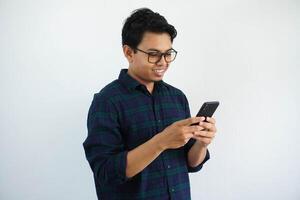 sonriente o contento cara joven asiático hombre mientras utilizando móvil teléfono aislado blanco antecedentes foto