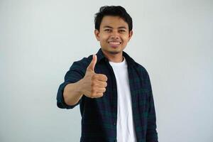 joven asiático hombre sonriente contento a el cámara y dar pulgar arriba aislado en blanco antecedentes. foto