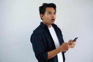 shocked young asian man while texting using mobile phone isolated on white background photo