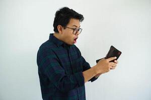 joven asiático hombre demostración conmocionado cara expresión mientras mirando a su billetera aislado en blanco antecedentes foto