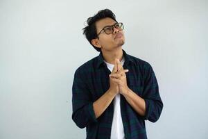 young asian man showing thinking gesture with his eyes looking up isolated on white background photo