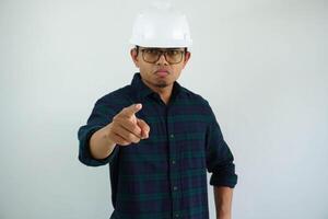 young asian architect man showing angry face expression while finger pointing forward isolated on white background photo