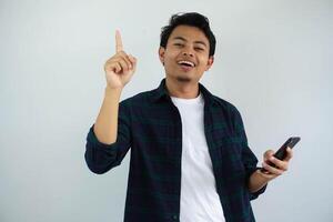 young asian man showing happy expression with finger pointing up when holding mobile phone isolated on white background photo