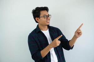 smiling young asian man looking and pointing to the left side with both hands isolated on white background photo