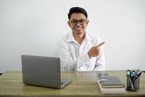 young asian businessman in a workplace pointing to the side to present a product wear white shirt isolated white background photo