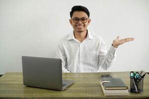 young asian businessman smiling in a workplace holding copy space imaginary on the palm to insert an ad wear white shirt isolated photo