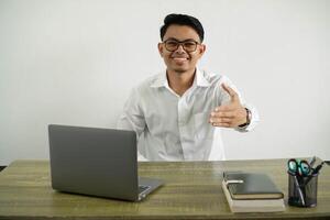 young asian businessman in a workplace shaking hands for closing a good deal, wear white shirt with glasses isolated photo