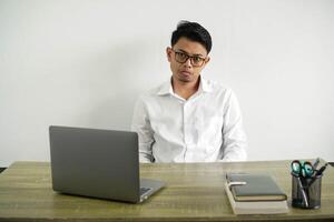 young asian businessman in a workplace with sad and depressed expression, wearing white shirt with glasses isolated photo