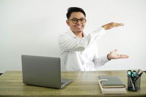 young asian businessman in a workplace holding copy space to insert an ad, wearing white shirt with glasses isolated photo