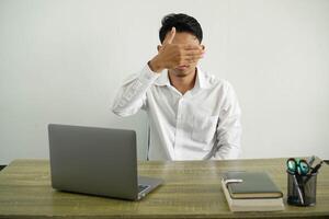 joven asiático empresario en un lugar de trabajo cubierta ojos por manos. hacer no querer a ver algo, vistiendo blanco camisa con lentes aislado foto