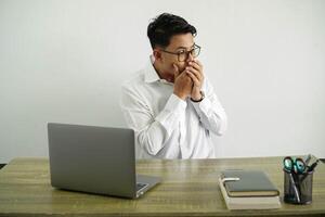 joven asiático empresario en un lugar de trabajo cubierta boca y mirando a el lado, vistiendo blanco camisa con lentes aislado foto